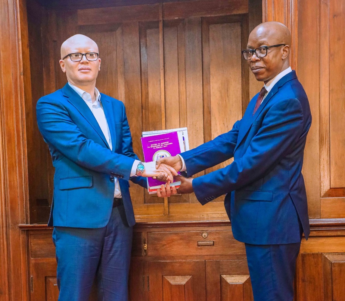 Dr Ally Possi (L), the solicitor general, receives token office documents from predecessor Dr Boniphace Luhende at the handing over ceremony in Dar es Salaam yesterday. 