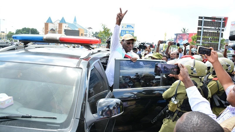 Opposition Chadema national Chairman Freeman Mbowe shows the victory sign from inside a police car in Dar es Salaam yesterday morning shortly after he was arrested apparently in connection with alleged participation in a banned protest march. 