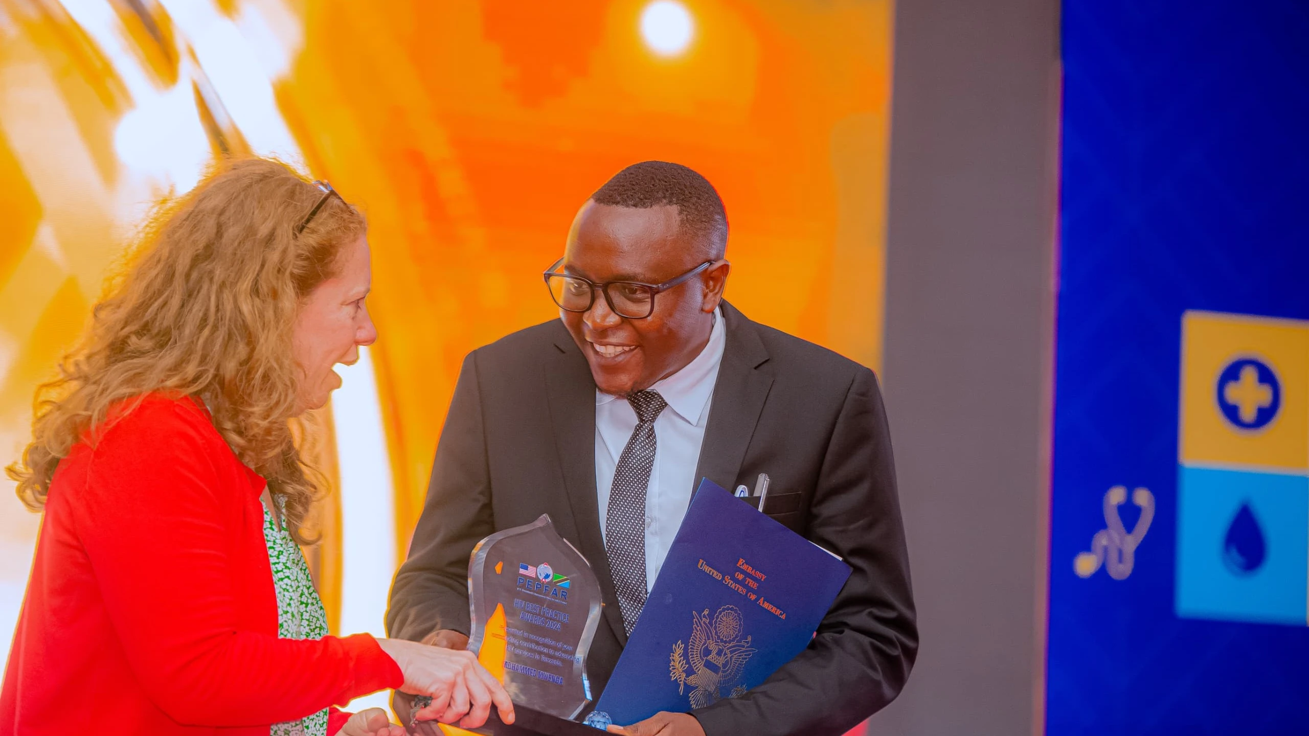 Mohamed Mwenga, senior social behaviour change advisor for the USAID ‘Afya Yangu’ southern project receives the 2024 PEPFAR HIV best practice award from PEPFAR Country Coordinator, Jessica Greene. 