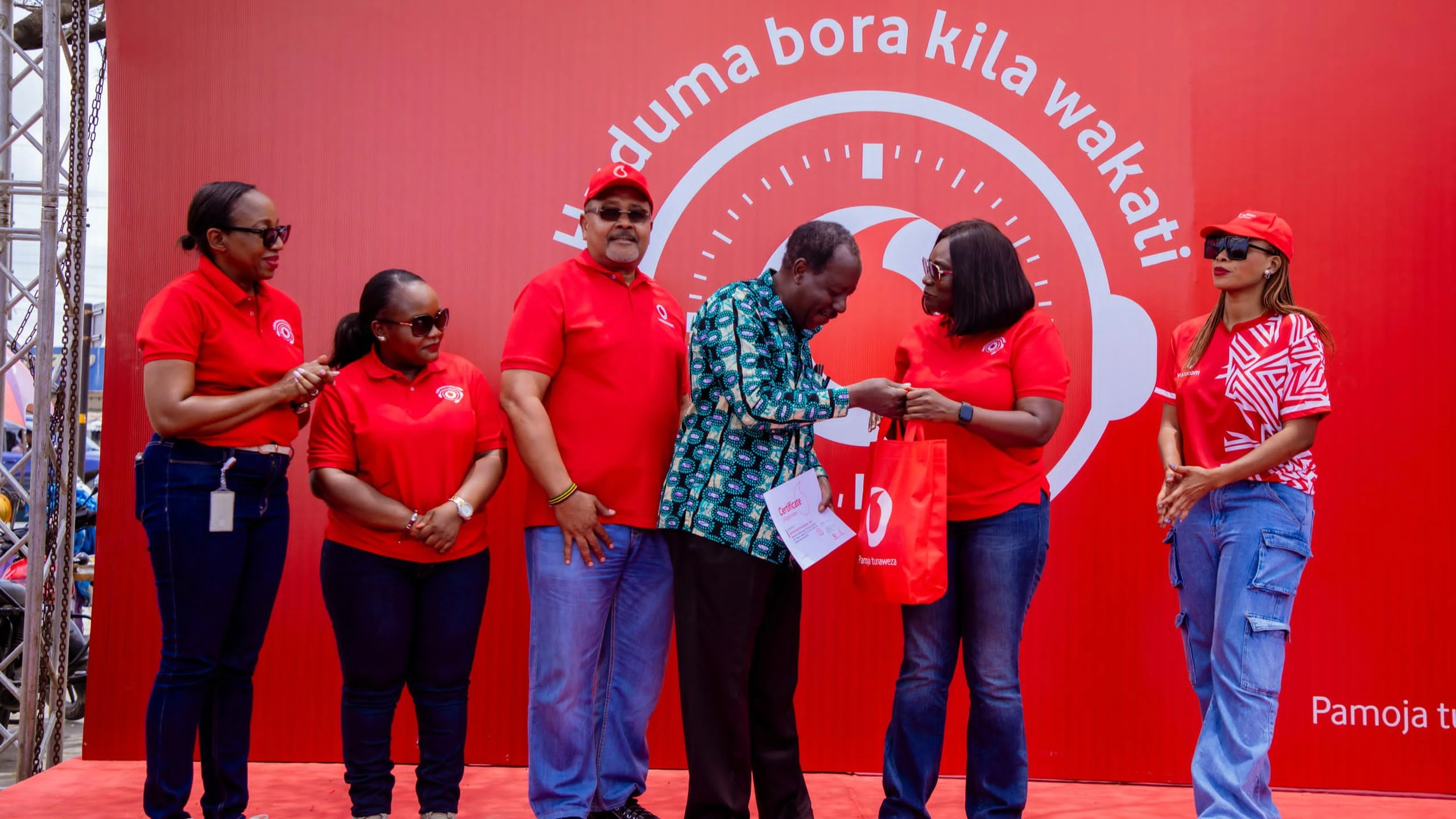 George Nyamugali (fourth from the left), a long-time Vodacom Tanzania Plc customer receiving a reward from Customer Service Director Harriet Lwakatare during the Customer Service Week celebrations recently held at Mabibo Market Centre in Dar es Salaam.