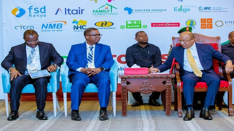 The President of Zanzibar, Dr Hussein Mwinyi (R), writes something before officially opening the 40th meeting of the African Union for Housing Finance (AUHF), organized in collaboration with the International Secondary Mortgage Markets Association (ISMMA)