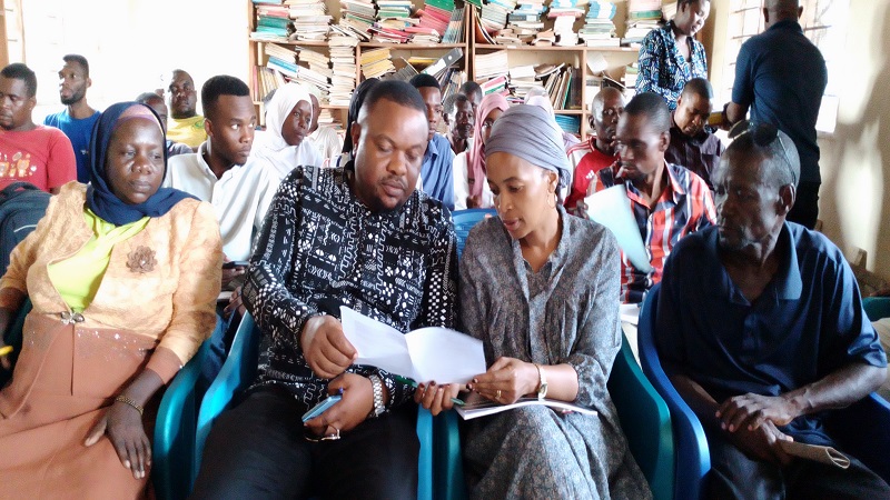 Mtwara District Commissioner, Abdallah Mwaipaya (L - seated) go through   a document detailing the sales   of cashew   auctions at the   farmers’ cooperative union    in   Masasi, and Nanyumbu districts    in Mtwara Region.