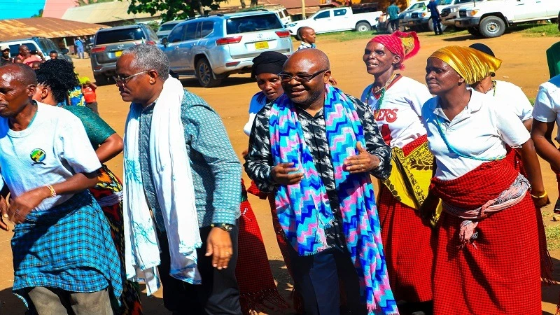 Prof. Kitila Mkumbo (wearing blue-striped scarf around his neck), Minister of State in the President's Office (Planning and Investment), dance with a group of performers during his visit to Galapo Ward in Babati District, Manyara Region on Monday.