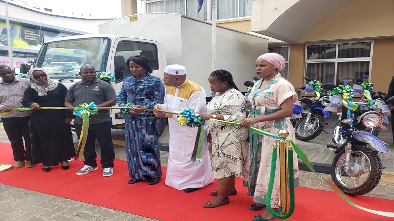 Rosemary Senyamule (C), the Dodoma regional commissioner, cutting the ribbon to launch a car and nine motorcycles for distributing vaccines to health centres in the region