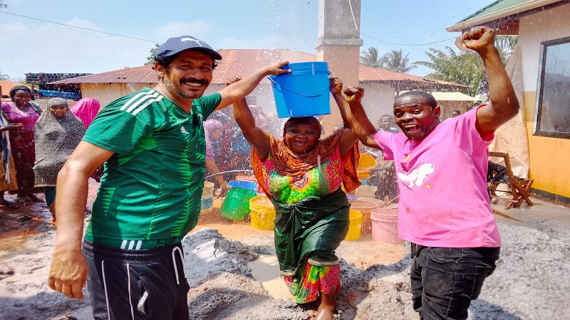 Mohamed Alnahdi (L), resident director (Tanzania) of Saudi Arabia’s Mo Maji Drilling and Dam Construction Agency, in jovial mood yesterday while assisting a resident of Kwemuyu in Muheza District in drawing water from one of 101 deep wells.