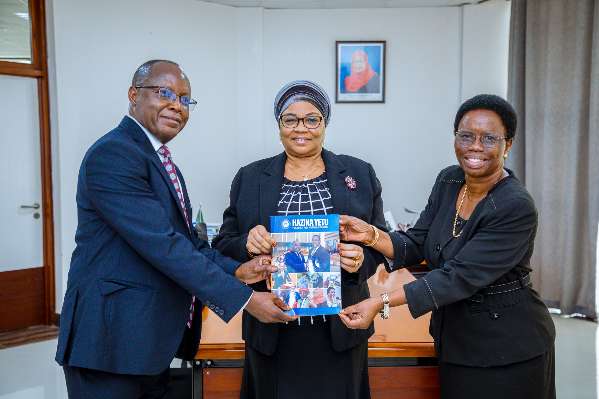 Dr Natu El-Maamry Mwamba (C), the Treasury permanent secretary, receives a departmental magazine from her deputy Jenifa Christian Omolo (R) and communications unit head, Benny Mwaipaja in Dodoma city on Tuesday.