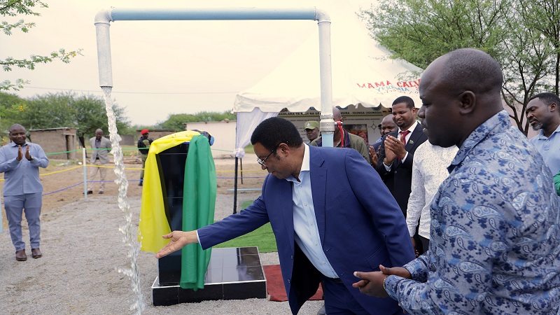 Prime Minister Kassim Majaliwa looks at water from a pipe when laying the foundation stone for Lake Victoria water network expansion project from Mkomero to Mgongoro yesterday.  Right is Water minister Jumaa Aweso