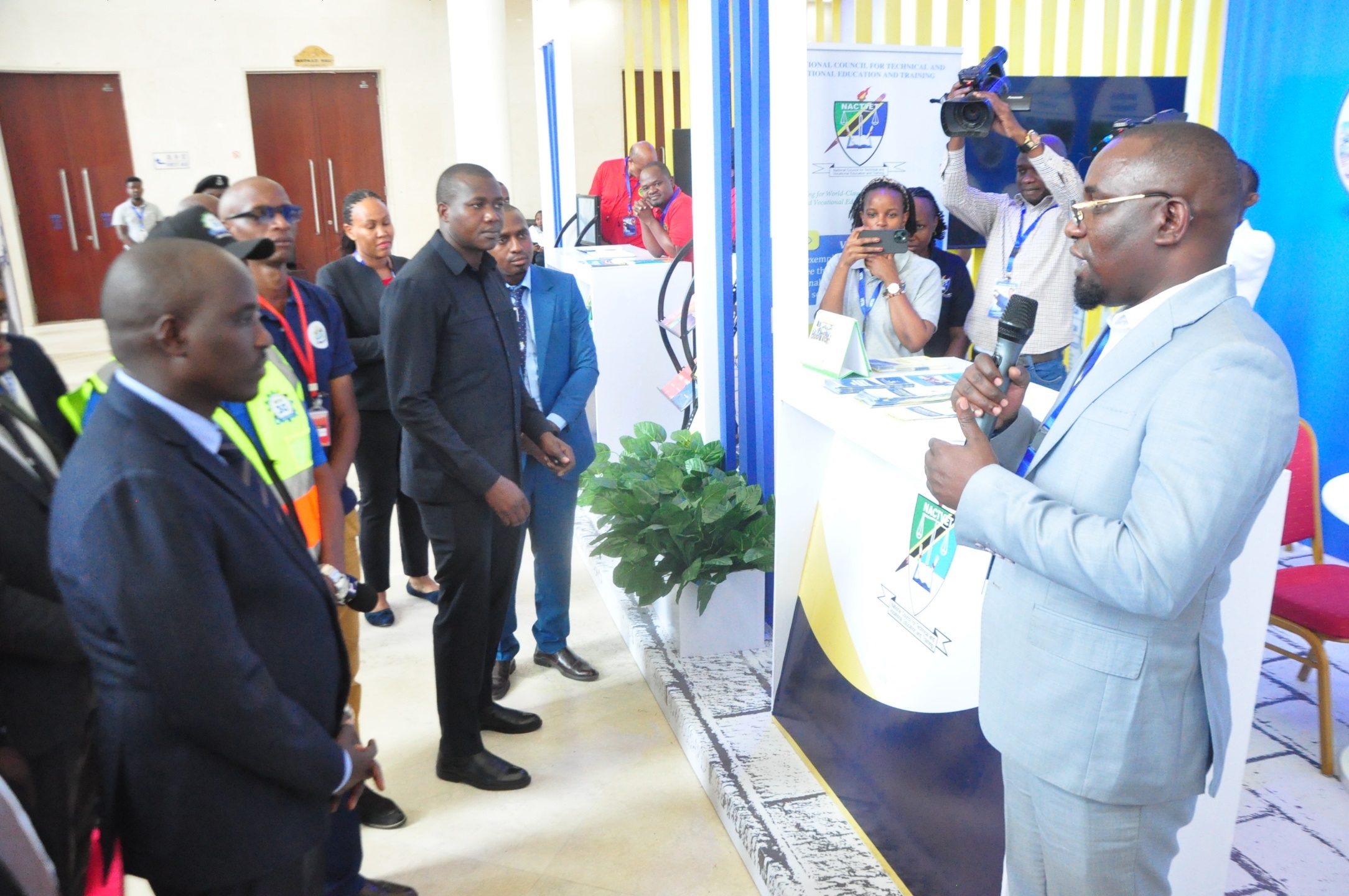 Deputy Prime Minister, Dr. Dotto Biteko (L) listens to Quality Assurance Director of National Council for Technical Education and Vocational Training (NACTVET), Dr. Jofrey Oleke, as he visited at their booth during the closing of the conference.