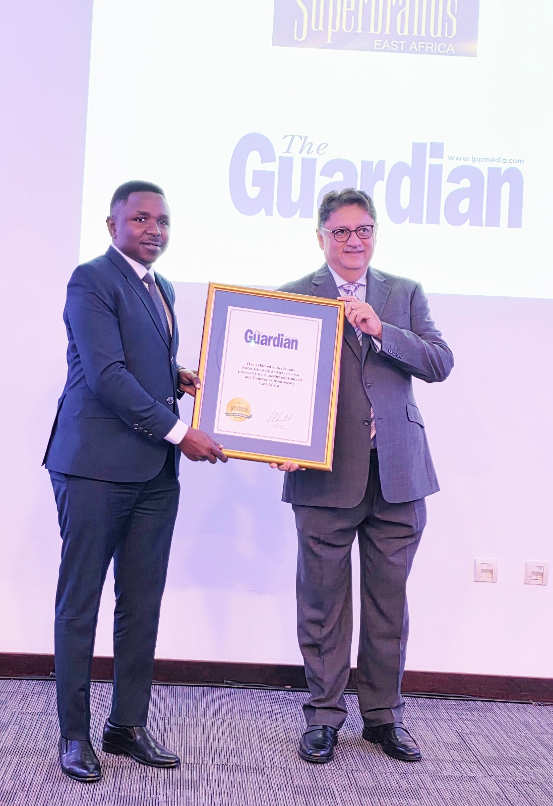 Superbrands East Africa CEO Jawad Jaffer (R) pictured in Dar es Salaam yesterday presenting to The Guardian Limited deputy general manager Jackson Paulo a Superbrands Award for 2024-2026 won by The Guardian newspaper. 